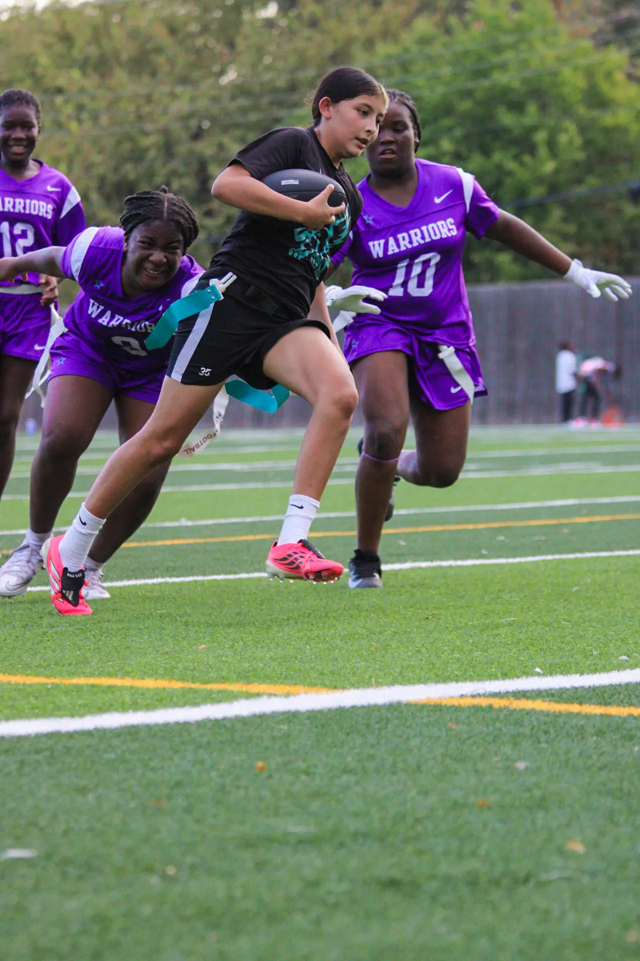 Jaylei breaking away with the ball as defenders chase during a varsity flag football game